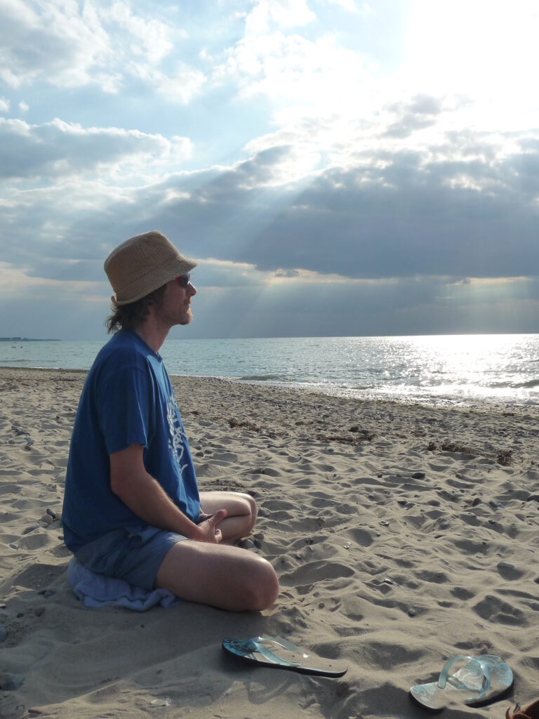 Tommy sitzt am Strand und schaut aufs Meer